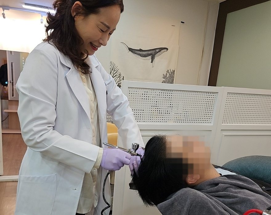아쿠아필링 핸드피스로 두피를 관리하는 장면